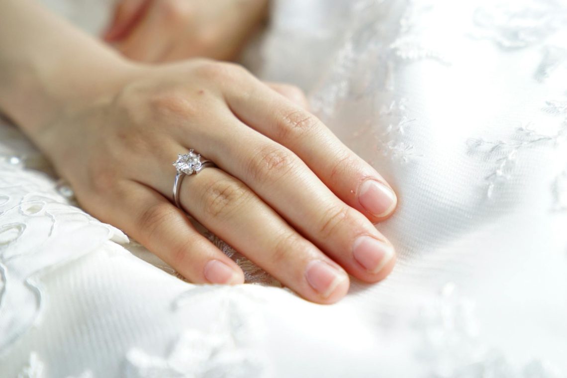 person wearing silver colored solitaire ring with clear gemstone